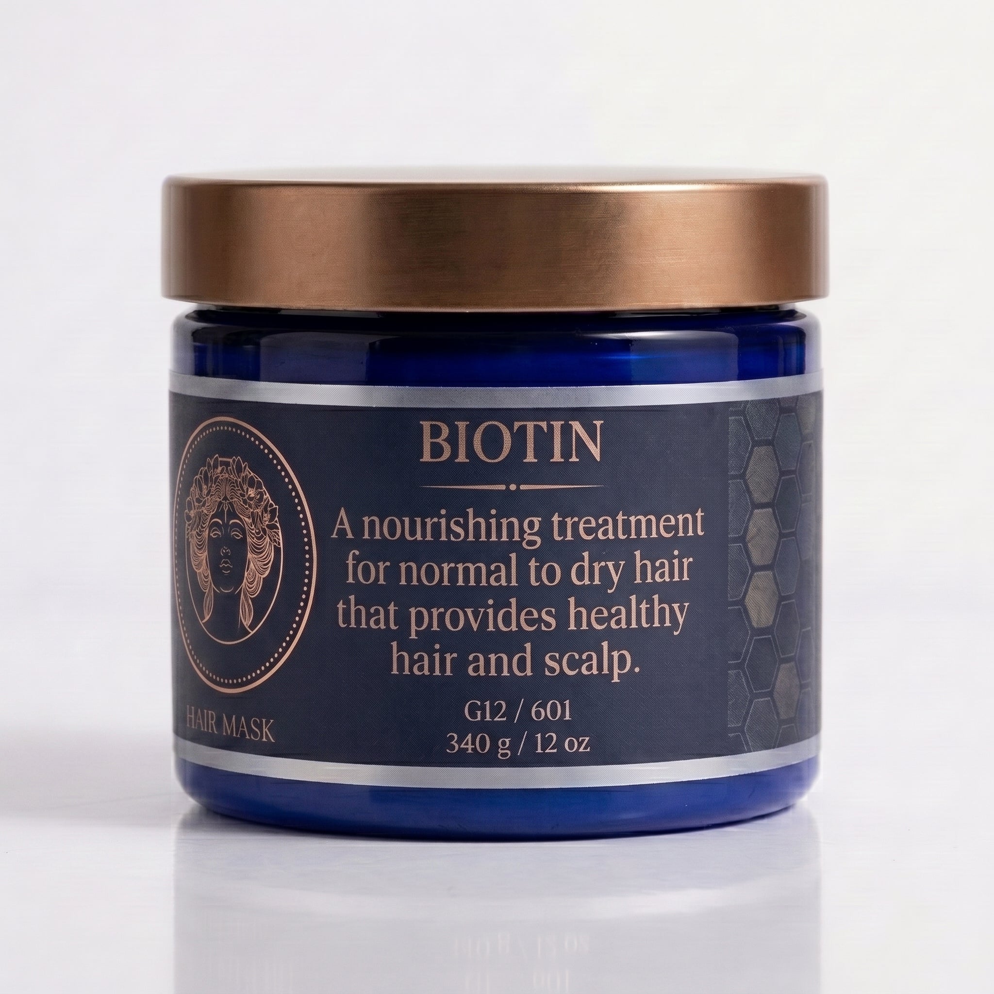A blue jar of Biotin Hair Mask with a metallic bronze lid, set against a clean white background with a soft reflection.